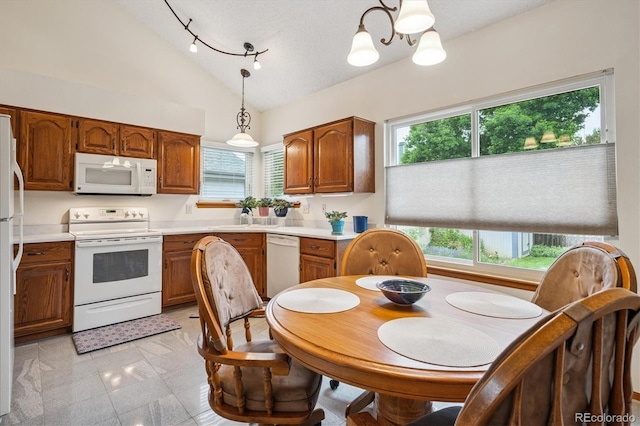 5513 S Yank Ct, Littleton, CO 80127 - kitchen with white appliances, vaulted ceiling, brown cabinetry, healthy amount of natural light, and decorative light fixtures