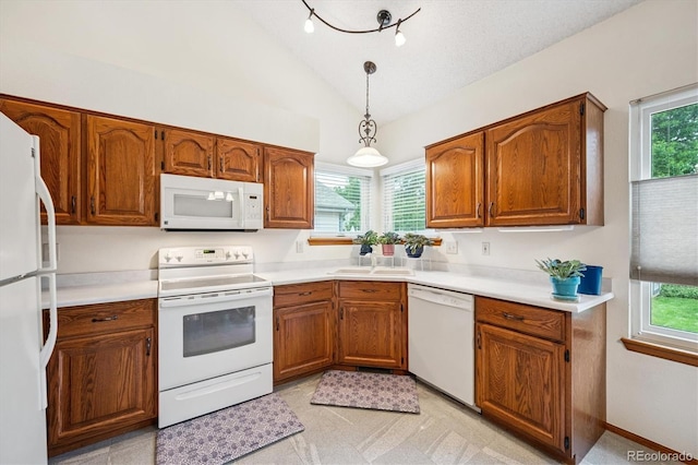 5513 S Yank Ct, Littleton, CO 80127 - kitchen with white appliances, brown cabinets, healthy amount of natural light, and vaulted ceiling