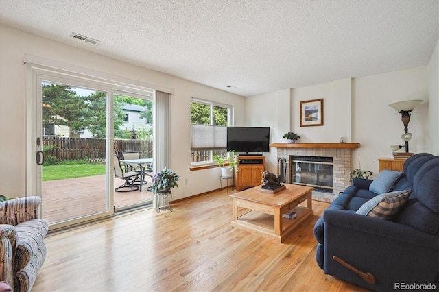 5513 S Yank Ct, Littleton, CO 80127 - living area with light wood-style flooring, a textured ceiling, and a fireplace