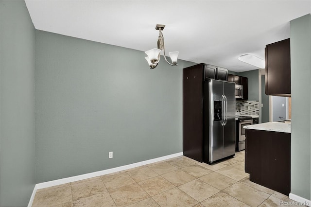 10211 Ura Ln Unit 208, Thornton, CO 80260 - kitchen with appliances with stainless steel finishes, light countertops, tasteful backsplash, hanging light fixtures, and dark brown cabinetry