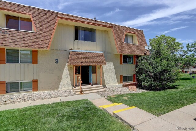 10211 Ura Ln Unit 208, Thornton, CO 80260 - view of front of house featuring roof with shingles, mansard roof, and a front lawn
