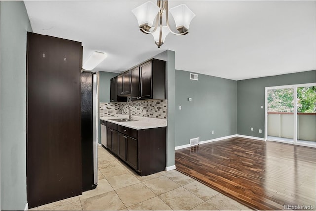 10211 Ura Ln Unit 208, Thornton, CO 80260 - kitchen featuring a chandelier, light countertops, decorative backsplash, dark brown cabinetry, and light wood-type flooring