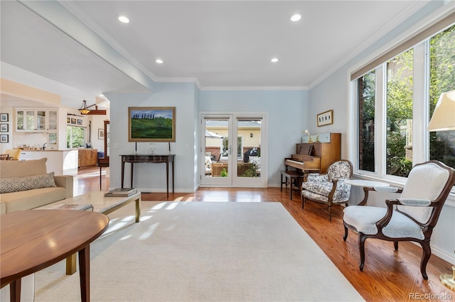 living room featuring crown molding, a healthy amount of sunlight, and light hardwood / wood-style flooring