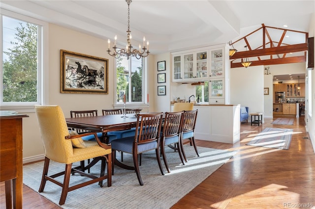 dining room with a raised ceiling, a chandelier, and light hardwood / wood-style flooring