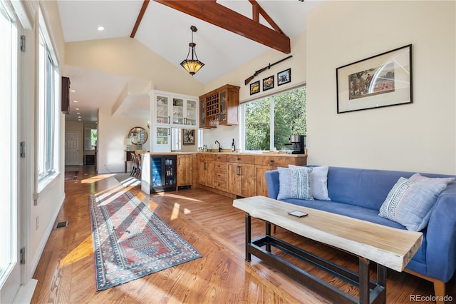 living room featuring wine cooler, indoor bar, light hardwood / wood-style floors, and high vaulted ceiling