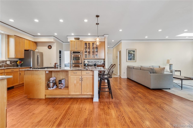 kitchen with stainless steel appliances, a kitchen bar, light stone countertops, and an island with sink