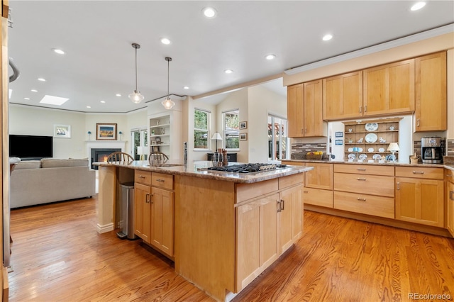 kitchen featuring light brown cabinetry, a center island, and stainless steel gas stovetop