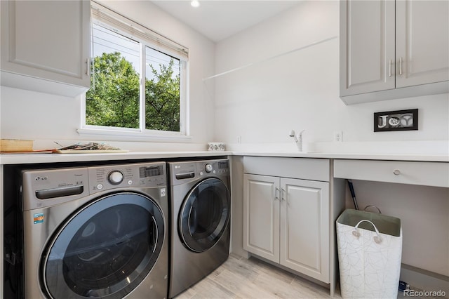 washroom featuring cabinets, sink, independent washer and dryer, and light hardwood / wood-style floors