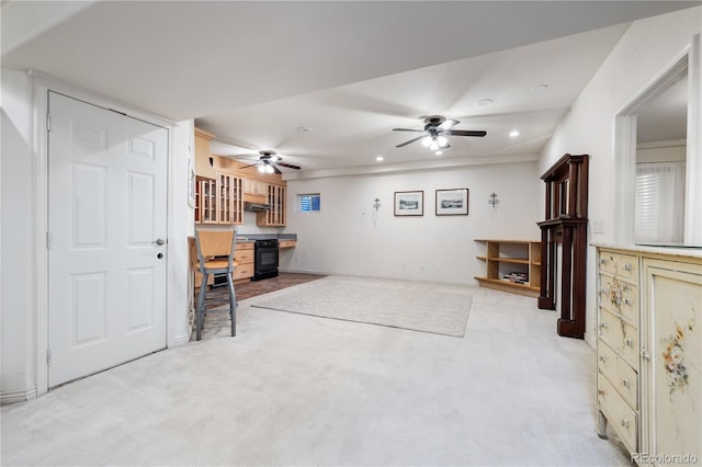 carpeted living room with ceiling fan and built in desk