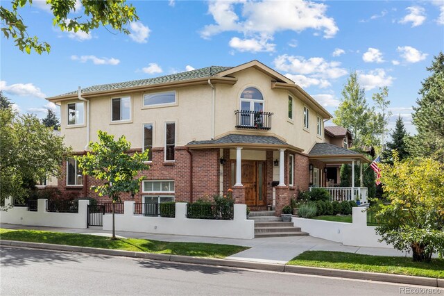 2400 S Clayton St, Denver, CO 80210 - view of front of house featuring a balcony, a fenced front yard, covered porch, stucco siding, and a gate