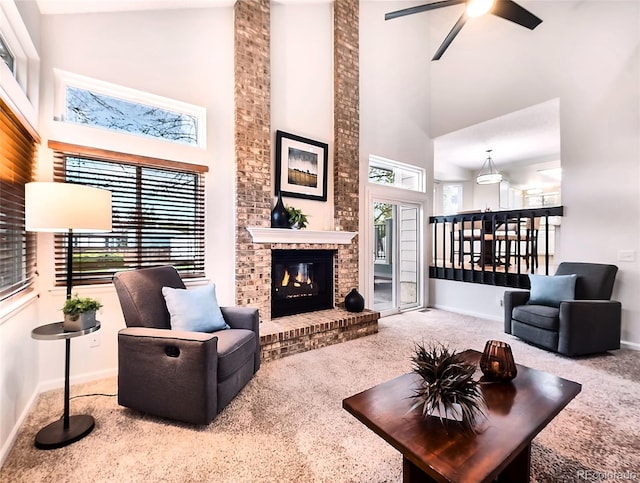 carpeted living area with a brick fireplace, a high ceiling, baseboards, and ceiling fan