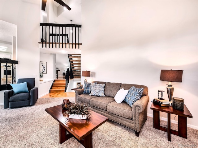 carpeted living room featuring baseboards, a high ceiling, and stairway