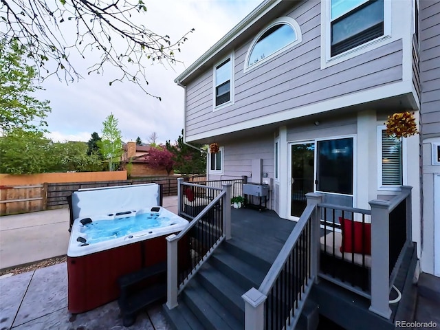 deck featuring a hot tub and fence