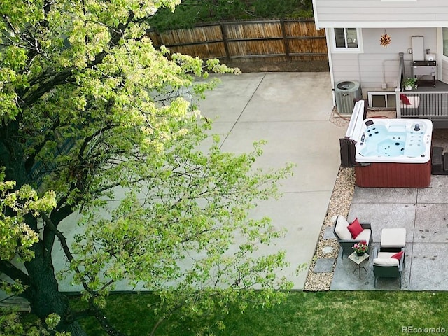 view of patio with central AC unit, a hot tub, and fence