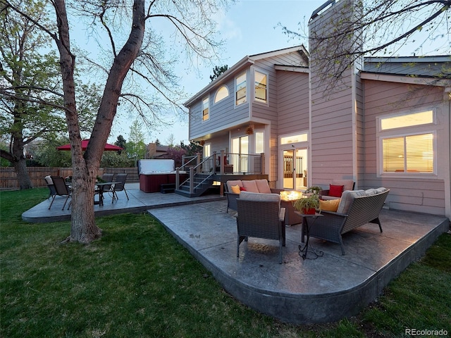 exterior space featuring a chimney, a hot tub, fence, a yard, and a patio
