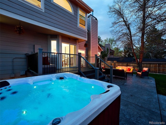wooden terrace with an outdoor living space, a fenced backyard, a hot tub, and a patio area