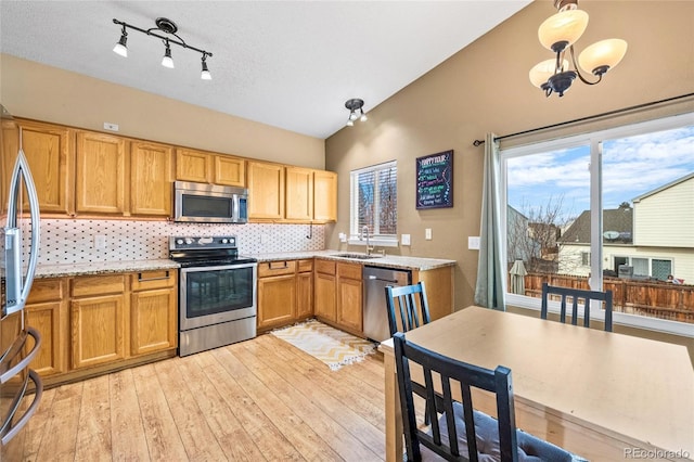 kitchen featuring light hardwood / wood-style flooring, hanging light fixtures, stainless steel appliances, decorative backsplash, and vaulted ceiling