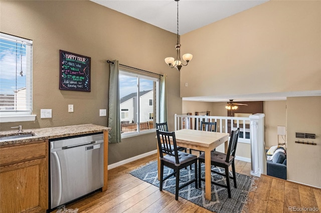 dining area featuring a healthy amount of sunlight, sink, ceiling fan with notable chandelier, and light wood-type flooring