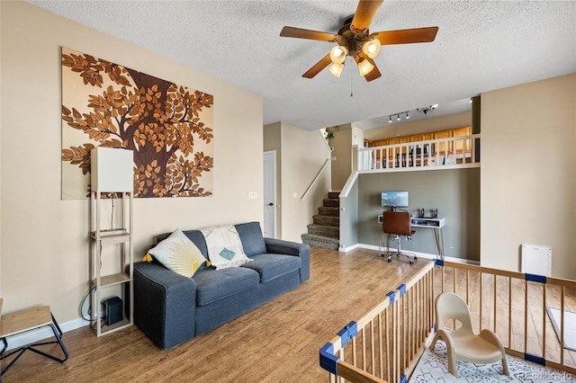 living room featuring ceiling fan, wood-type flooring, and a textured ceiling