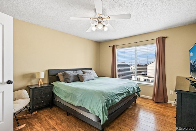 bedroom with ceiling fan, dark hardwood / wood-style floors, and a textured ceiling