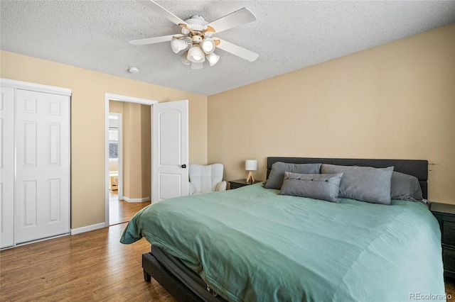 bedroom with ceiling fan, wood-type flooring, and a textured ceiling