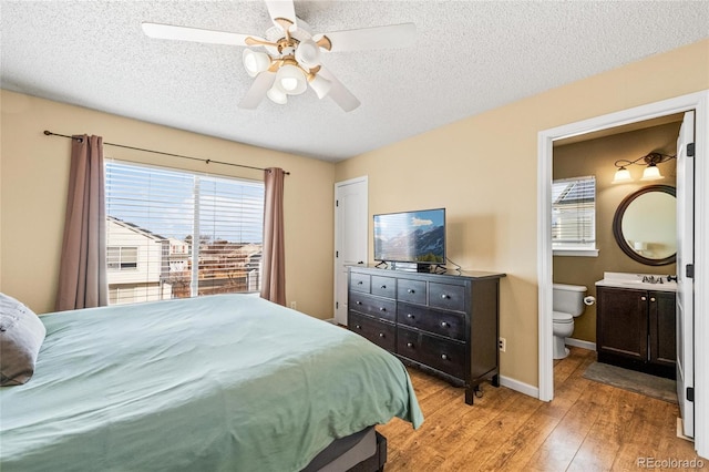 bedroom with sink, ceiling fan, ensuite bathroom, a textured ceiling, and light wood-type flooring