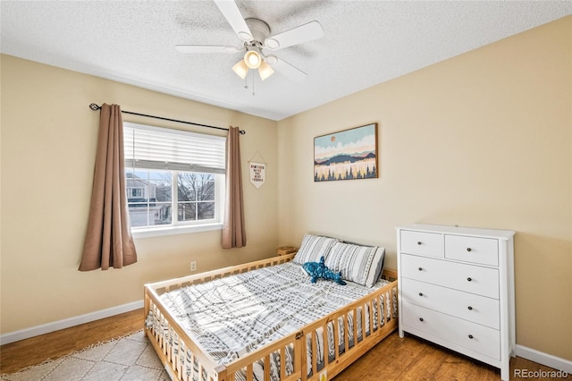 bedroom with ceiling fan, light hardwood / wood-style flooring, and a textured ceiling