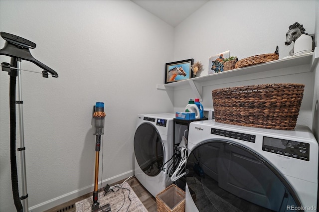 laundry room with washer and dryer, baseboards, and wood finished floors