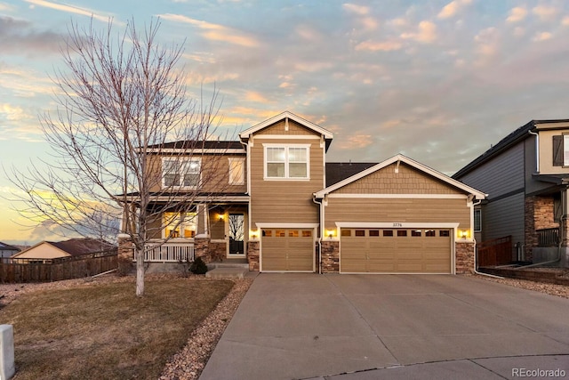 craftsman-style home with a porch, an attached garage, fence, stone siding, and driveway