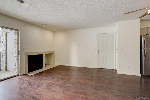 unfurnished living room featuring a textured ceiling, a tile fireplace, ceiling fan, and dark hardwood / wood-style floors