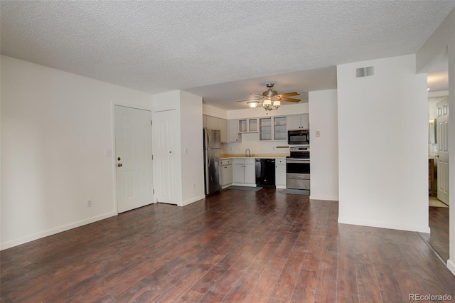 unfurnished living room with a textured ceiling, ceiling fan, dark wood-type flooring, and sink