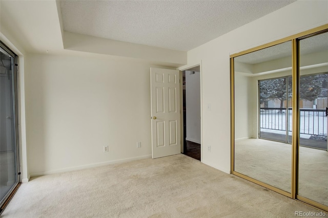 unfurnished bedroom featuring light carpet, a textured ceiling, access to exterior, and a closet