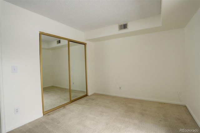 unfurnished bedroom featuring light carpet and a closet