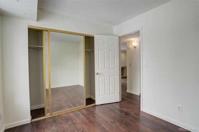 unfurnished bedroom with a textured ceiling, dark wood-type flooring, and a closet