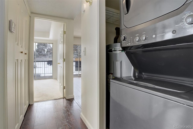 laundry room featuring dark hardwood / wood-style flooring and stacked washing maching and dryer