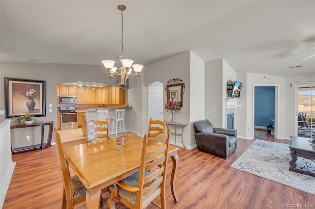 dining area featuring light hardwood / wood-style floors, lofted ceiling, and ceiling fan with notable chandelier