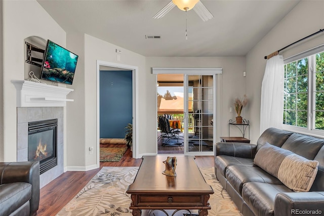 living room with hardwood / wood-style floors, a tile fireplace, and ceiling fan