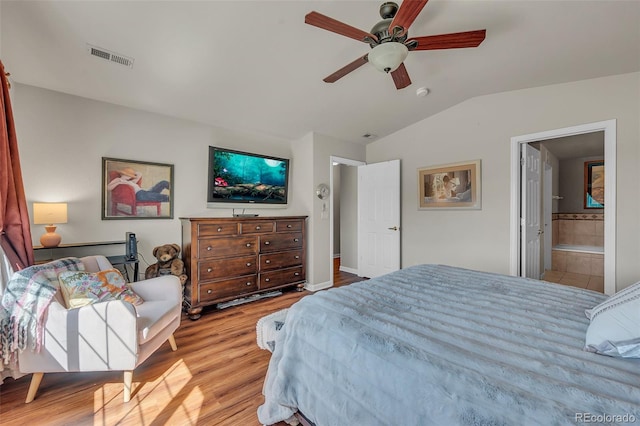 bedroom featuring connected bathroom, lofted ceiling, light wood-type flooring, and ceiling fan