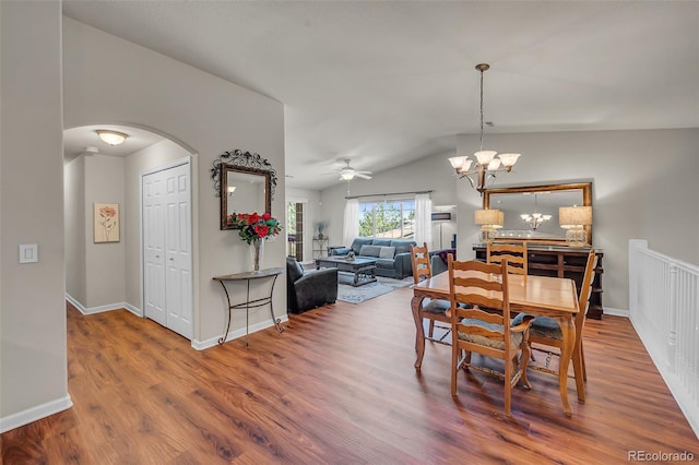 dining space with lofted ceiling, hardwood / wood-style flooring, and ceiling fan with notable chandelier