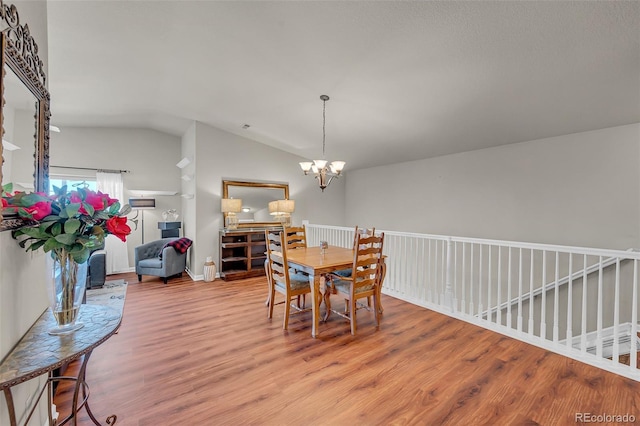 dining room with light hardwood / wood-style floors, a notable chandelier, and lofted ceiling