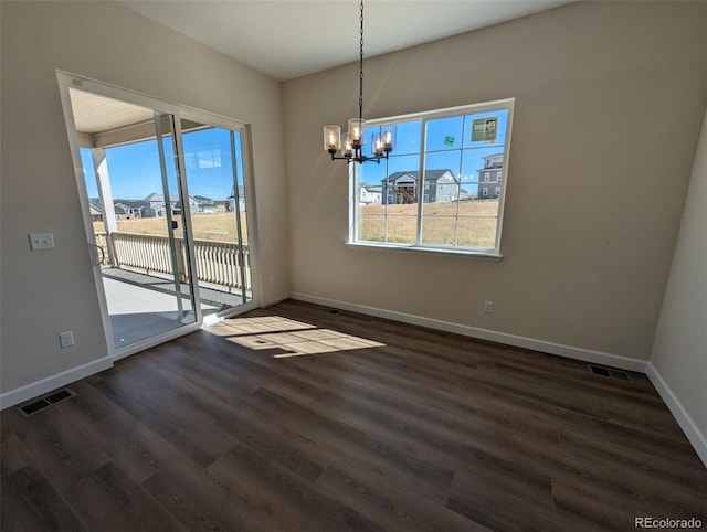 unfurnished dining area with a notable chandelier, a healthy amount of sunlight, and dark hardwood / wood-style flooring