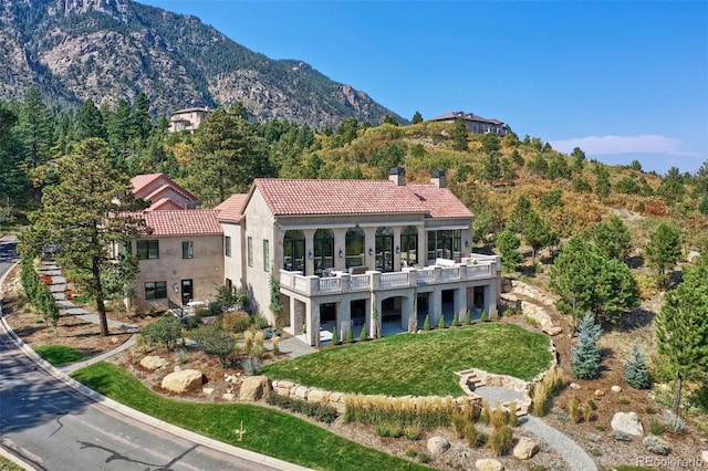 exterior space with a balcony, a mountain view, and a yard