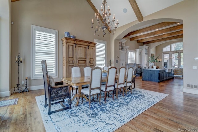 dining room featuring beam ceiling, an inviting chandelier, and light hardwood / wood-style floors