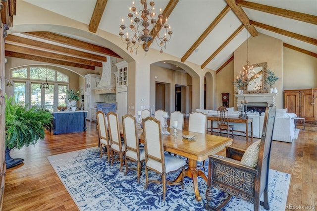 dining space with high vaulted ceiling, beam ceiling, wood-type flooring, and a chandelier