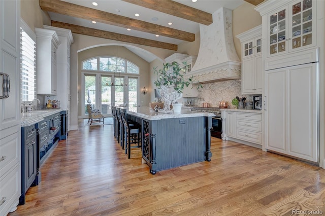 kitchen with premium range hood, a center island, light stone countertops, blue cabinetry, and white cabinets