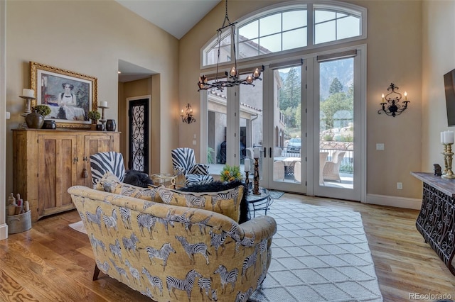 living room with a chandelier, light hardwood / wood-style flooring, and high vaulted ceiling