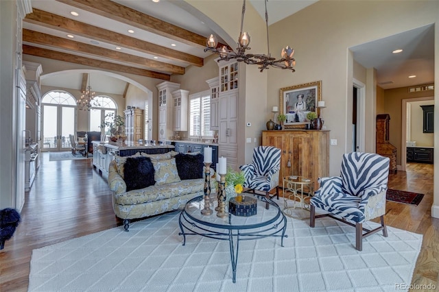 living room with a wealth of natural light, light hardwood / wood-style flooring, beam ceiling, and a chandelier