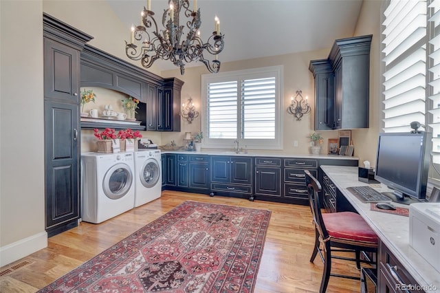 laundry area featuring light hardwood / wood-style floors, sink, a notable chandelier, and washing machine and dryer