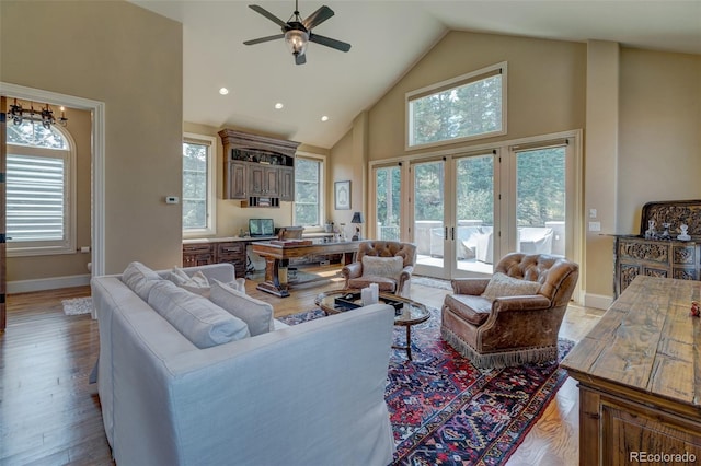 living room with high vaulted ceiling, french doors, ceiling fan, and light hardwood / wood-style flooring