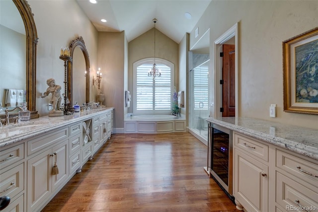 bathroom with wine cooler, vanity, vaulted ceiling, hardwood / wood-style floors, and an inviting chandelier